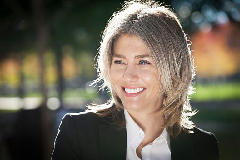 Smiling woman outdoors in professional attire.