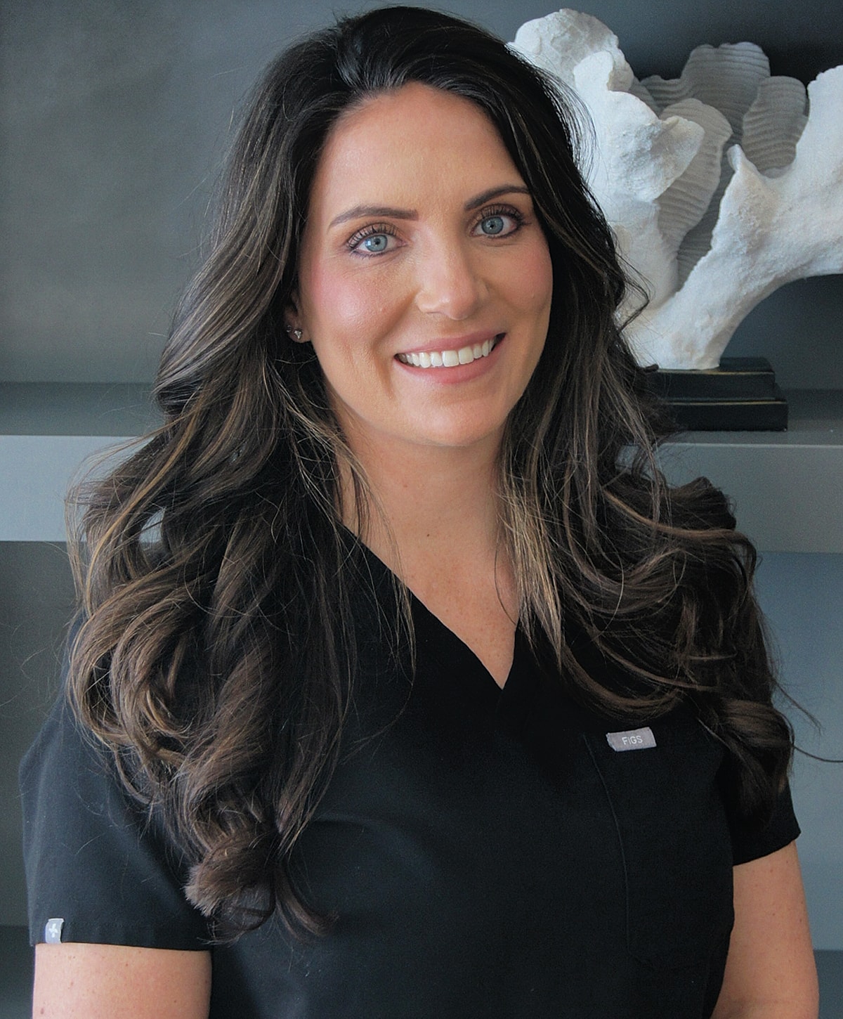 Smiling woman in black medical scrubs.