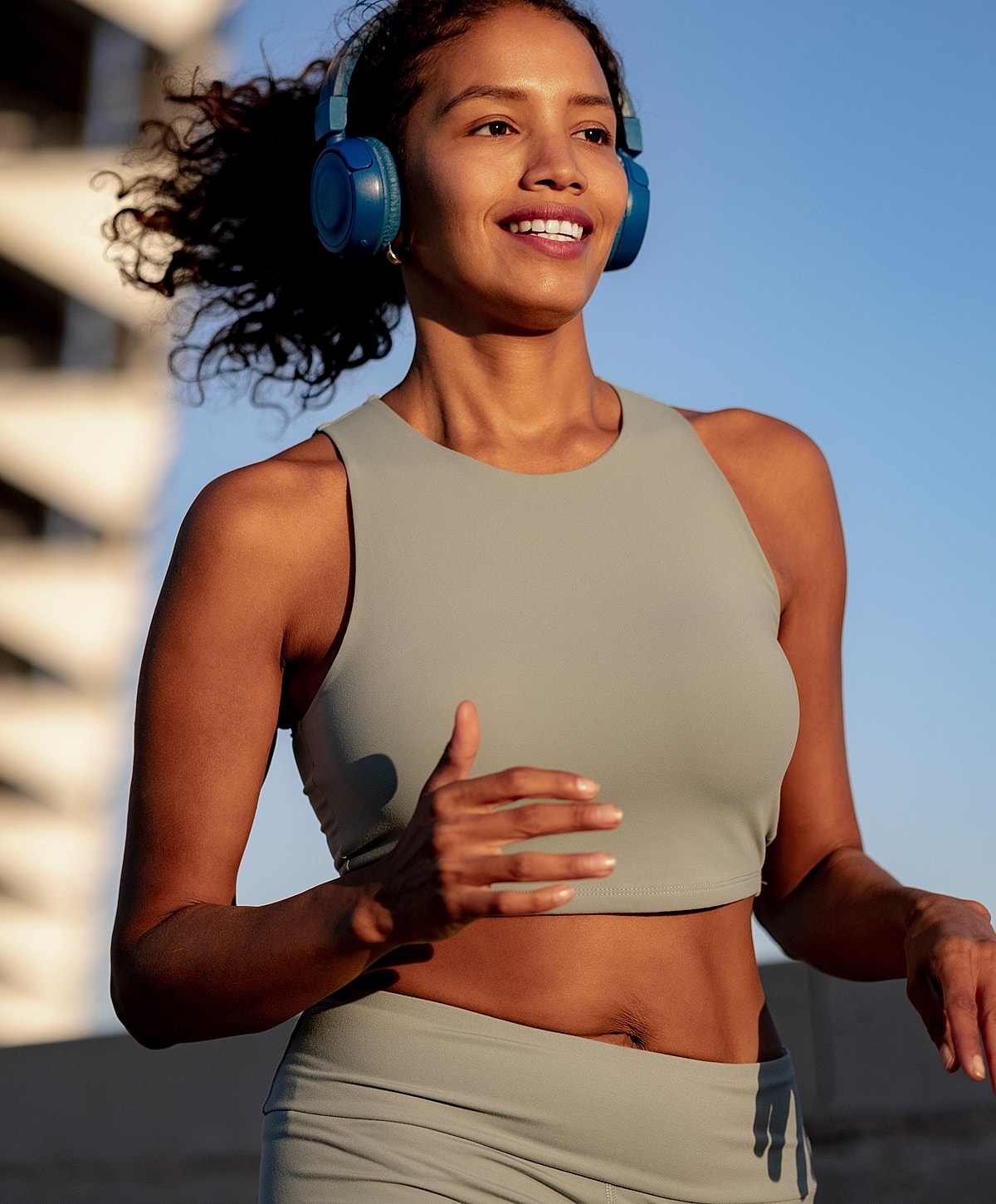 Woman jogging with headphones in outdoor setting.
