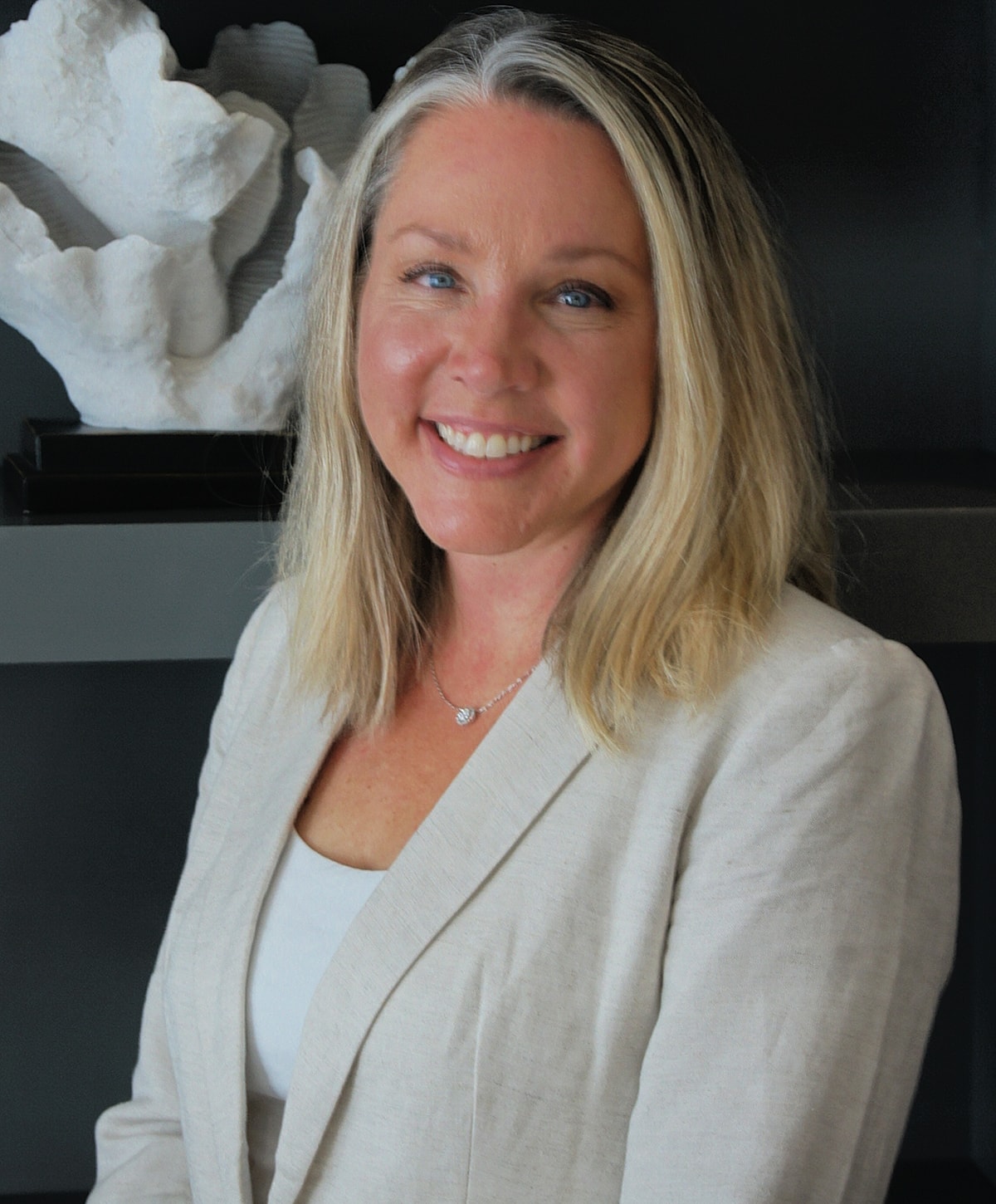 Professional woman smiling in a light-colored blazer.