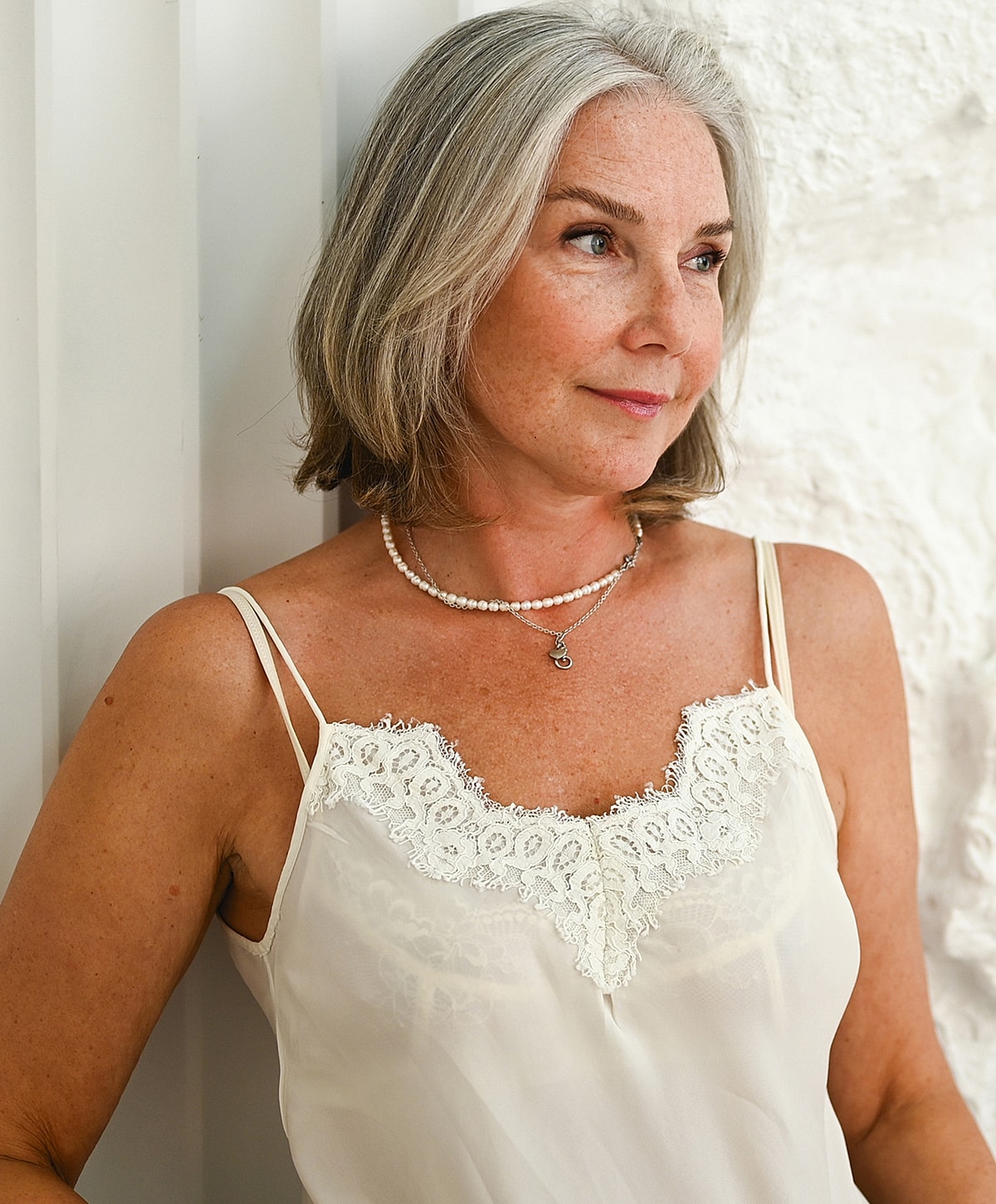 Woman in elegant lace top, gray hair.