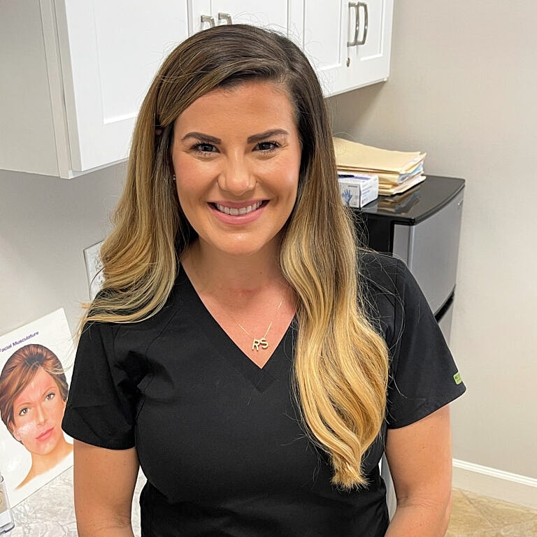 Smiling woman in medical scrubs at clinic.