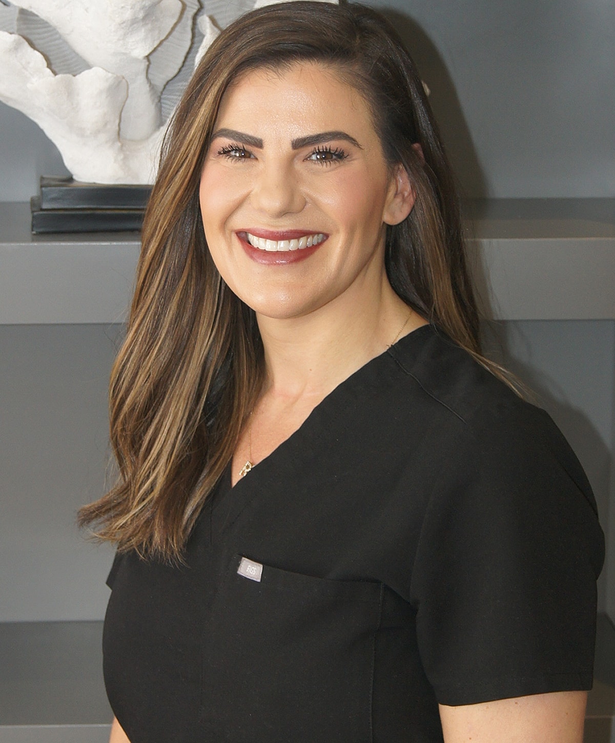 Smiling professional in black scrubs portrait.