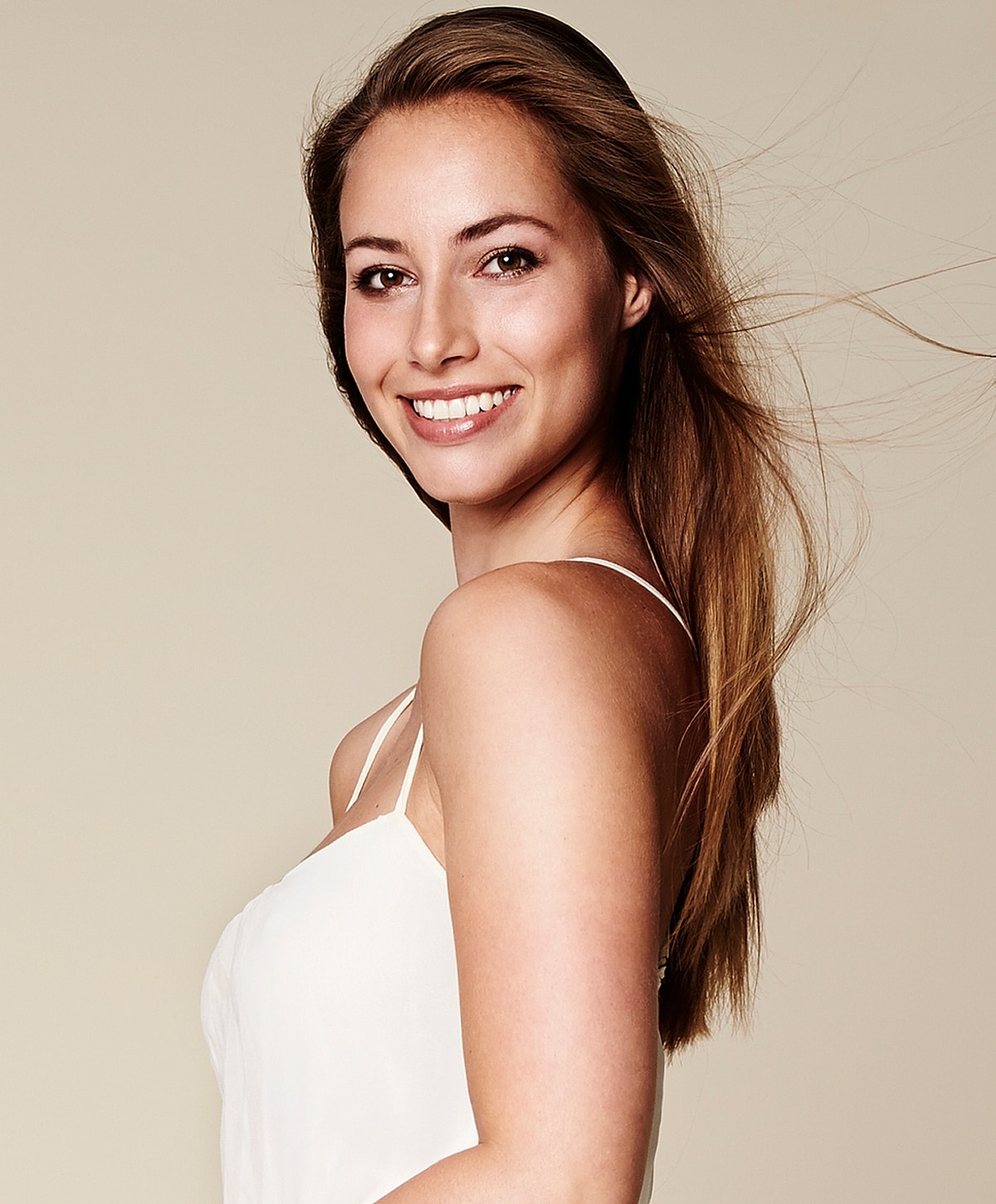 Smiling woman with long hair on neutral background.