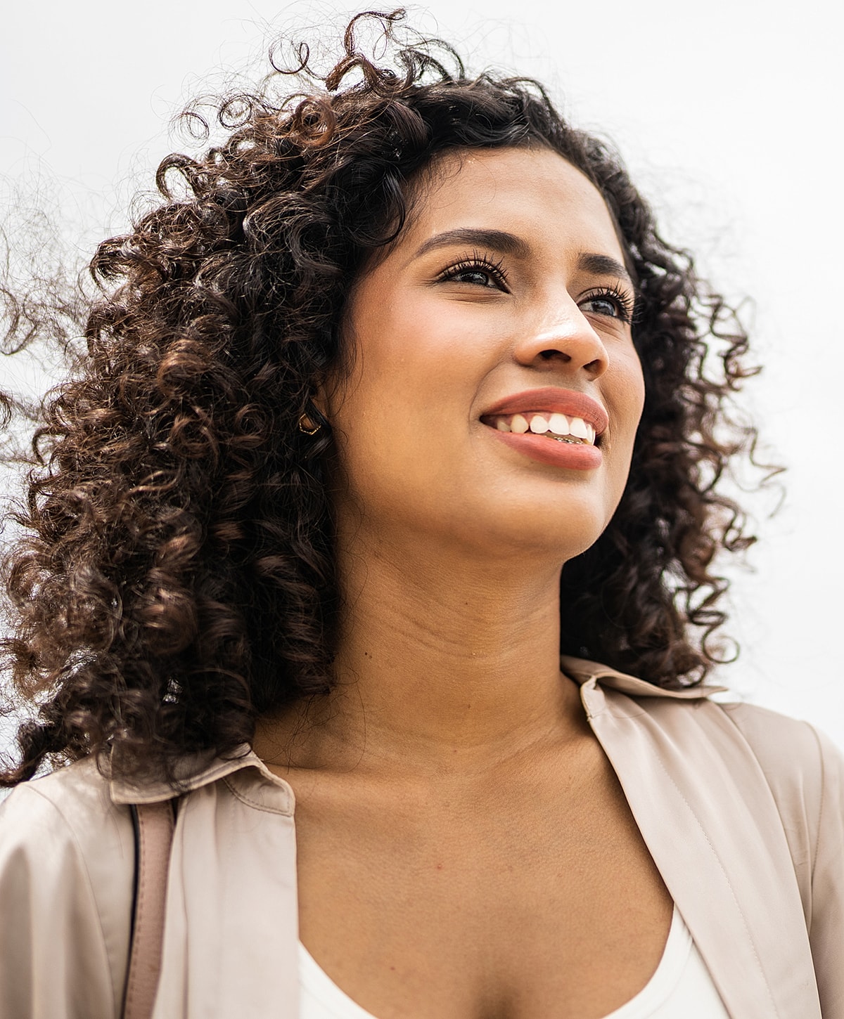 Smiling woman with curly hair looking upward.