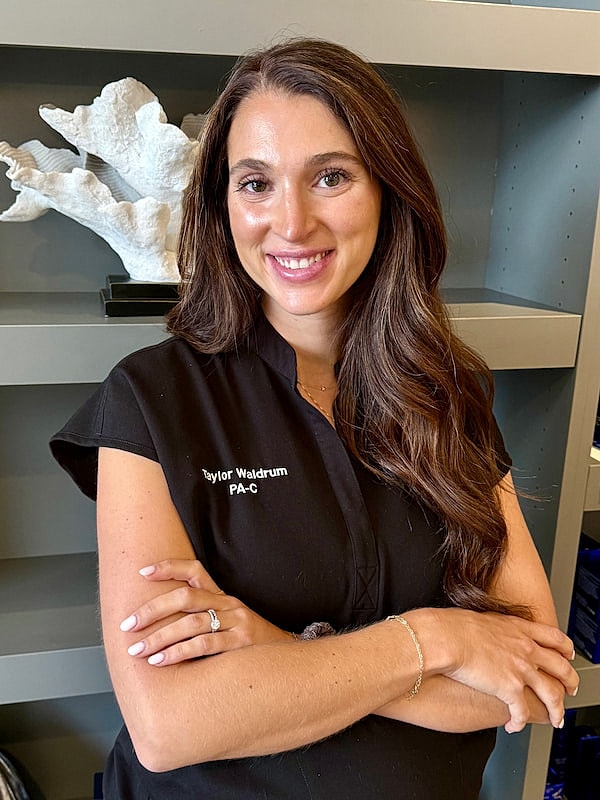Healthcare professional smiling with arms crossed.
