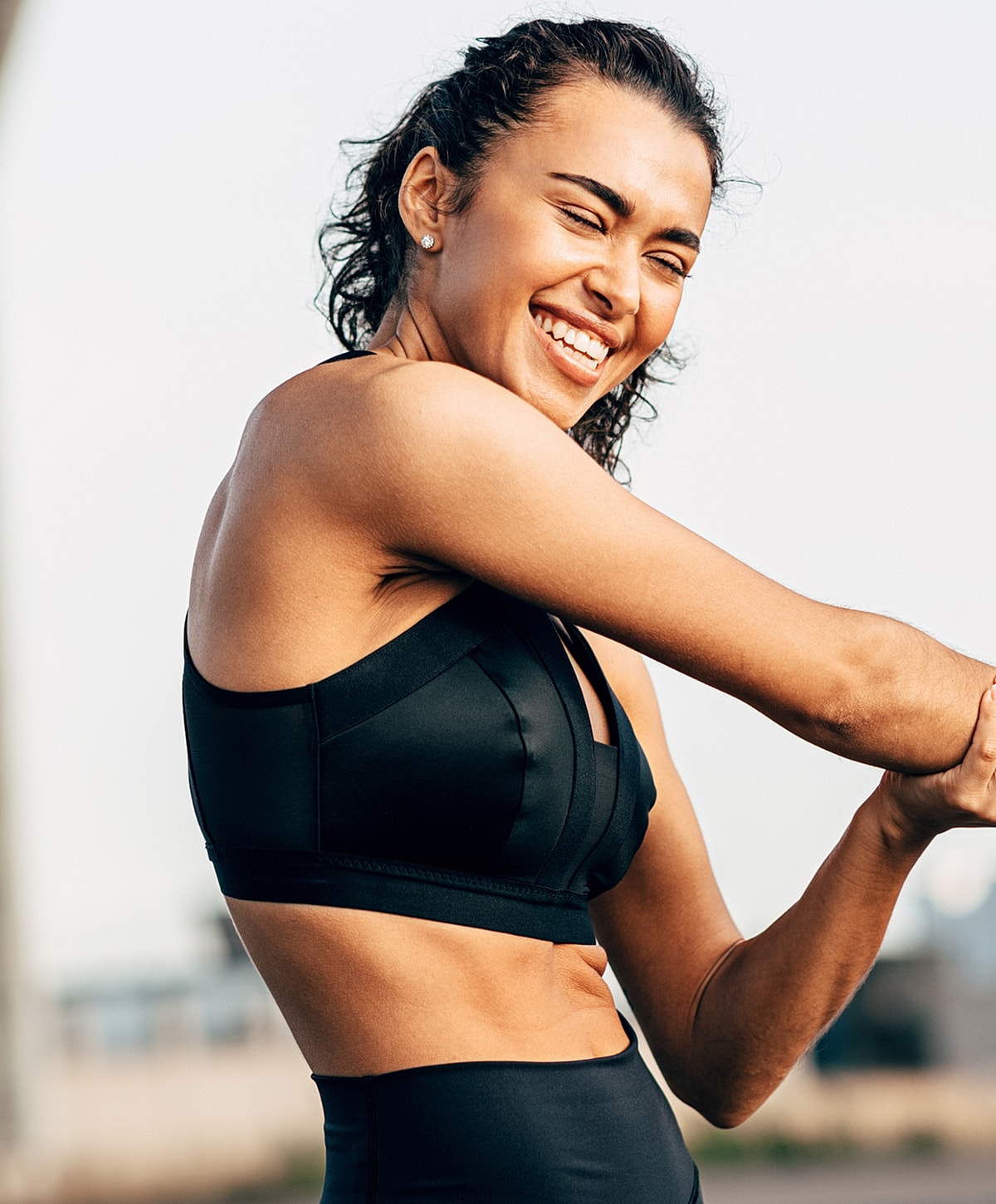Woman in activewear smiling outdoors.