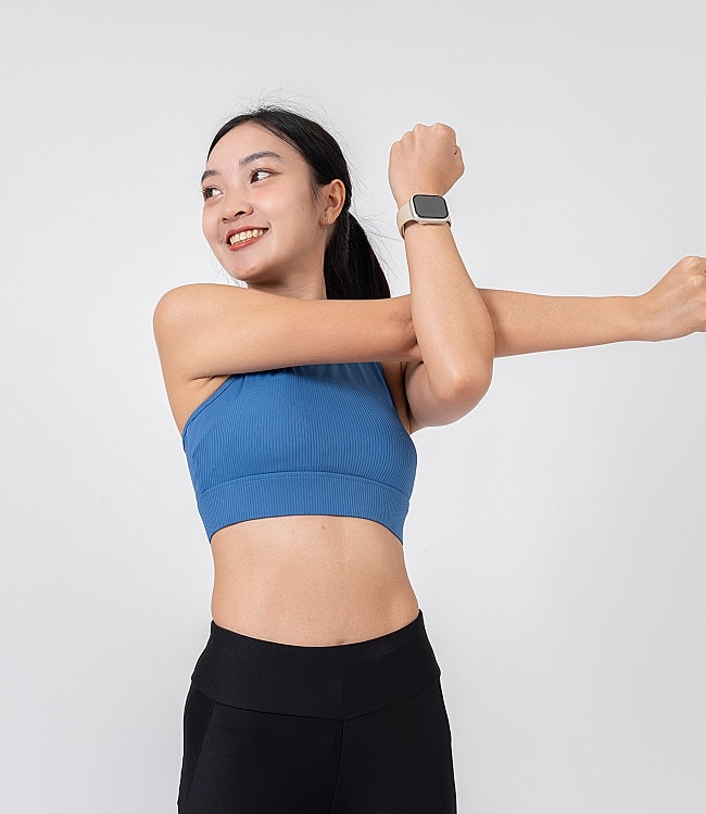 Woman stretching in athletic wear, smiling.