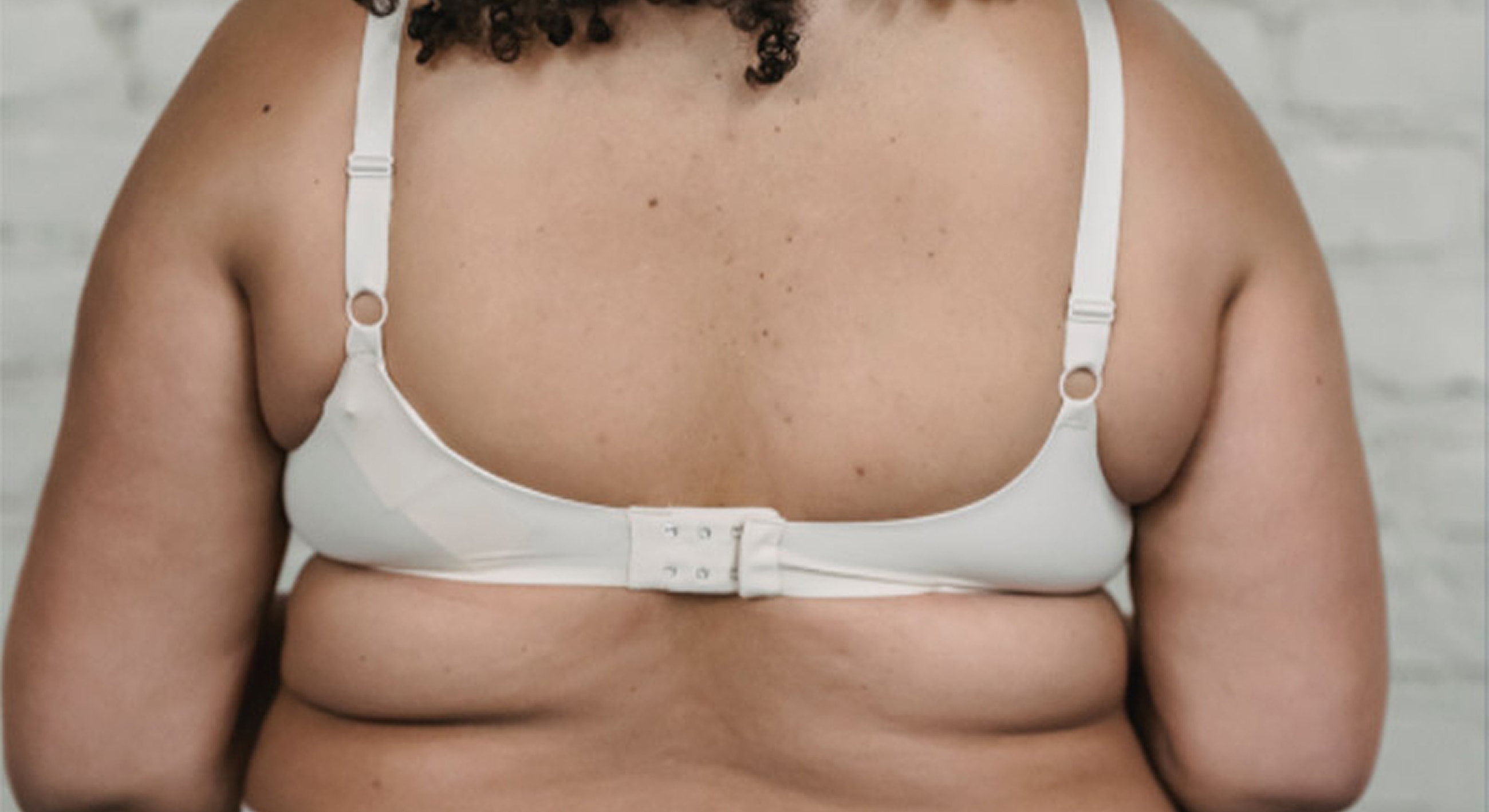 Back view of person wearing white bra.
