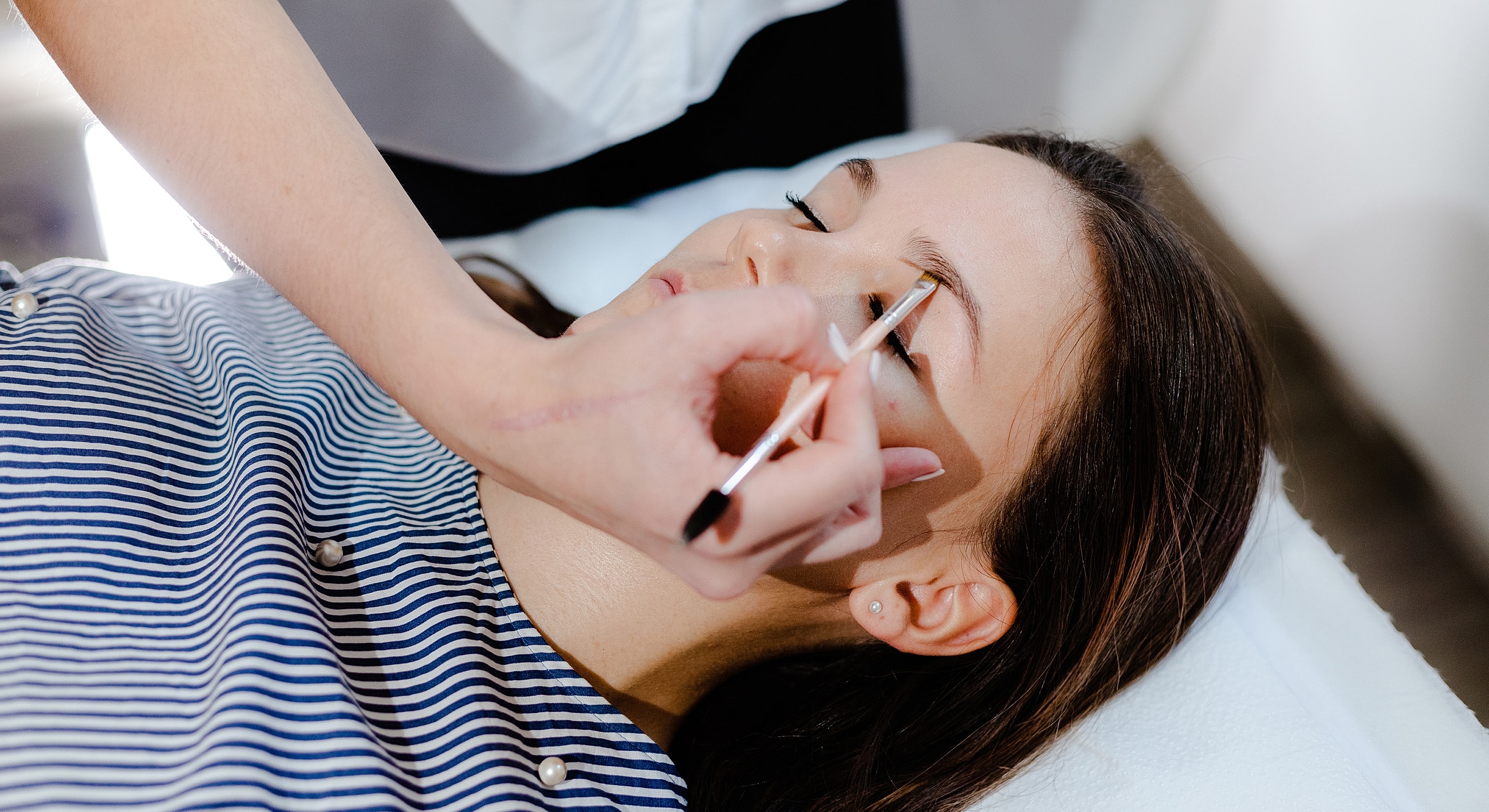 Applying makeup on a woman's eyebrows.