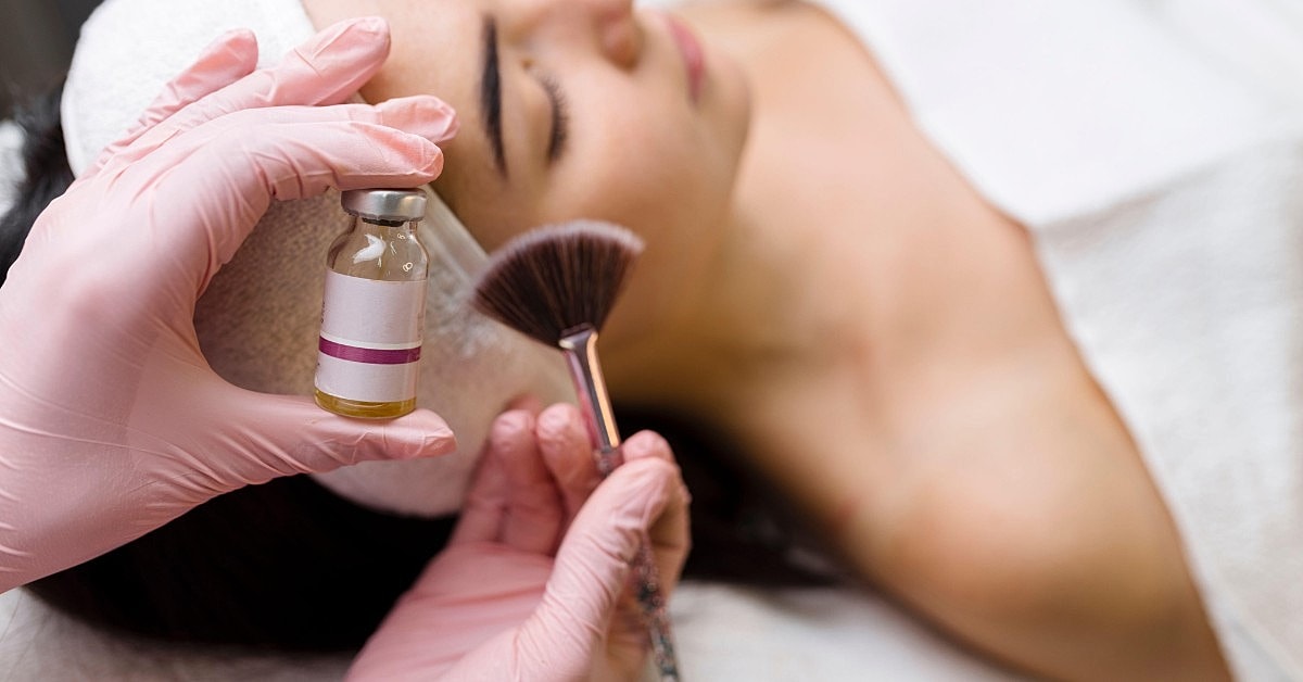 Cosmetologist applying treatment to client's face.