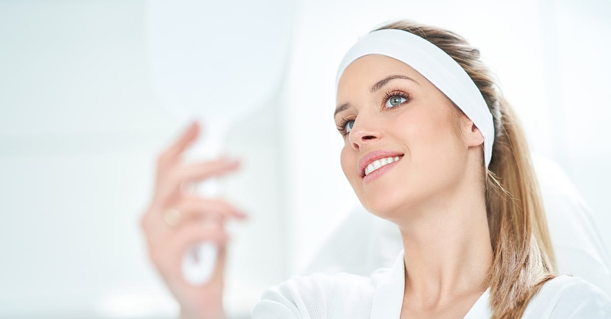 Smiling woman holding a mirror in spa environment.