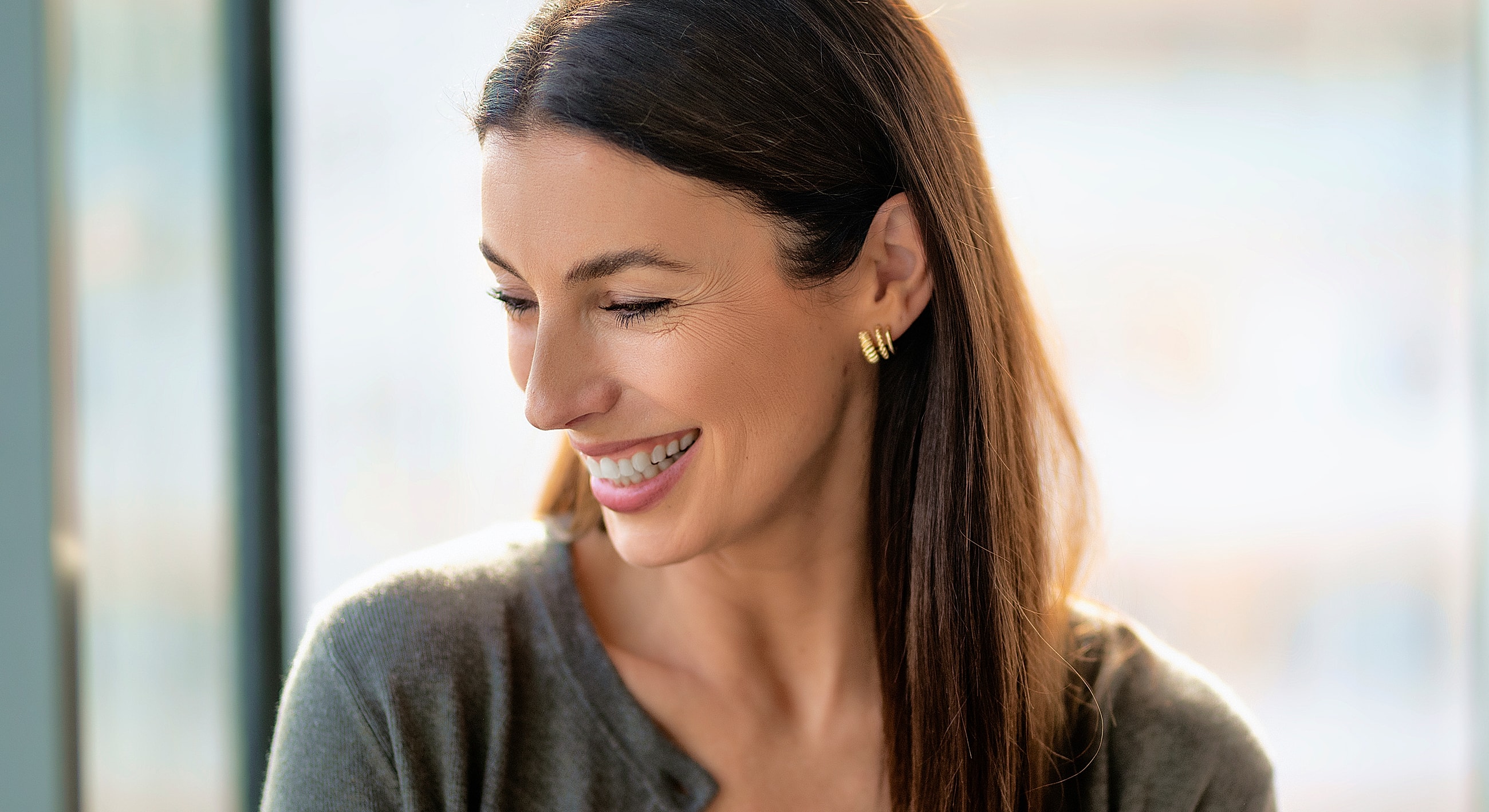 Smiling woman with long hair in soft light.
