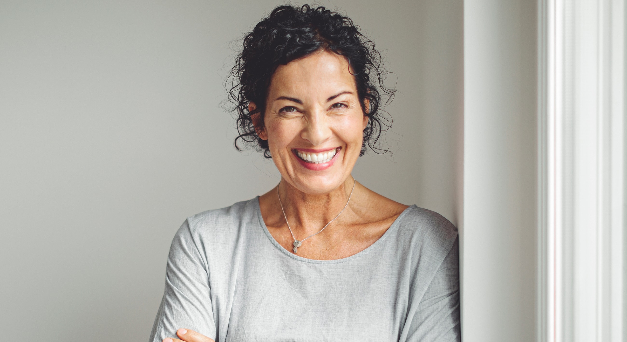 Smiling woman with curly hair in gray top.