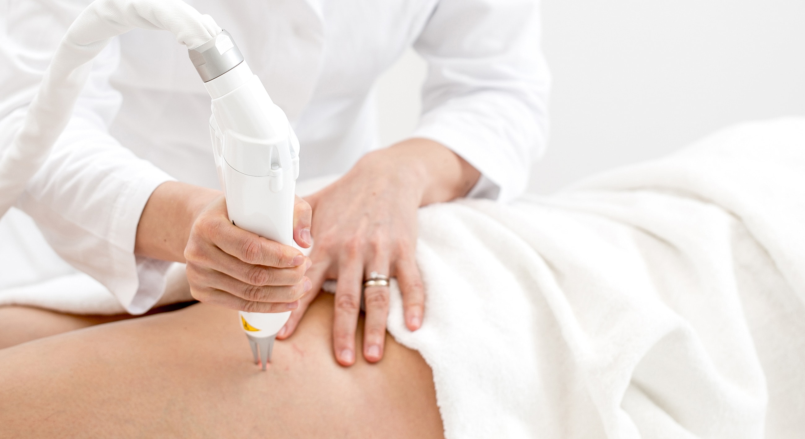 Doctor performing laser treatment on patient's skin.