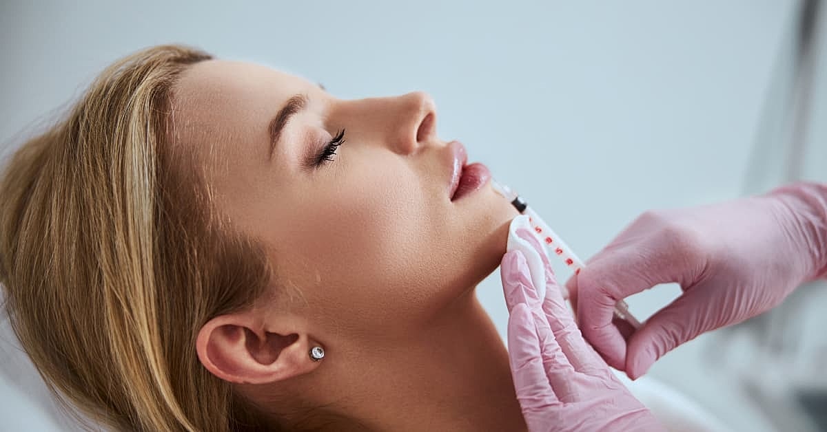 Woman receiving lip filler injections on her bottom lip