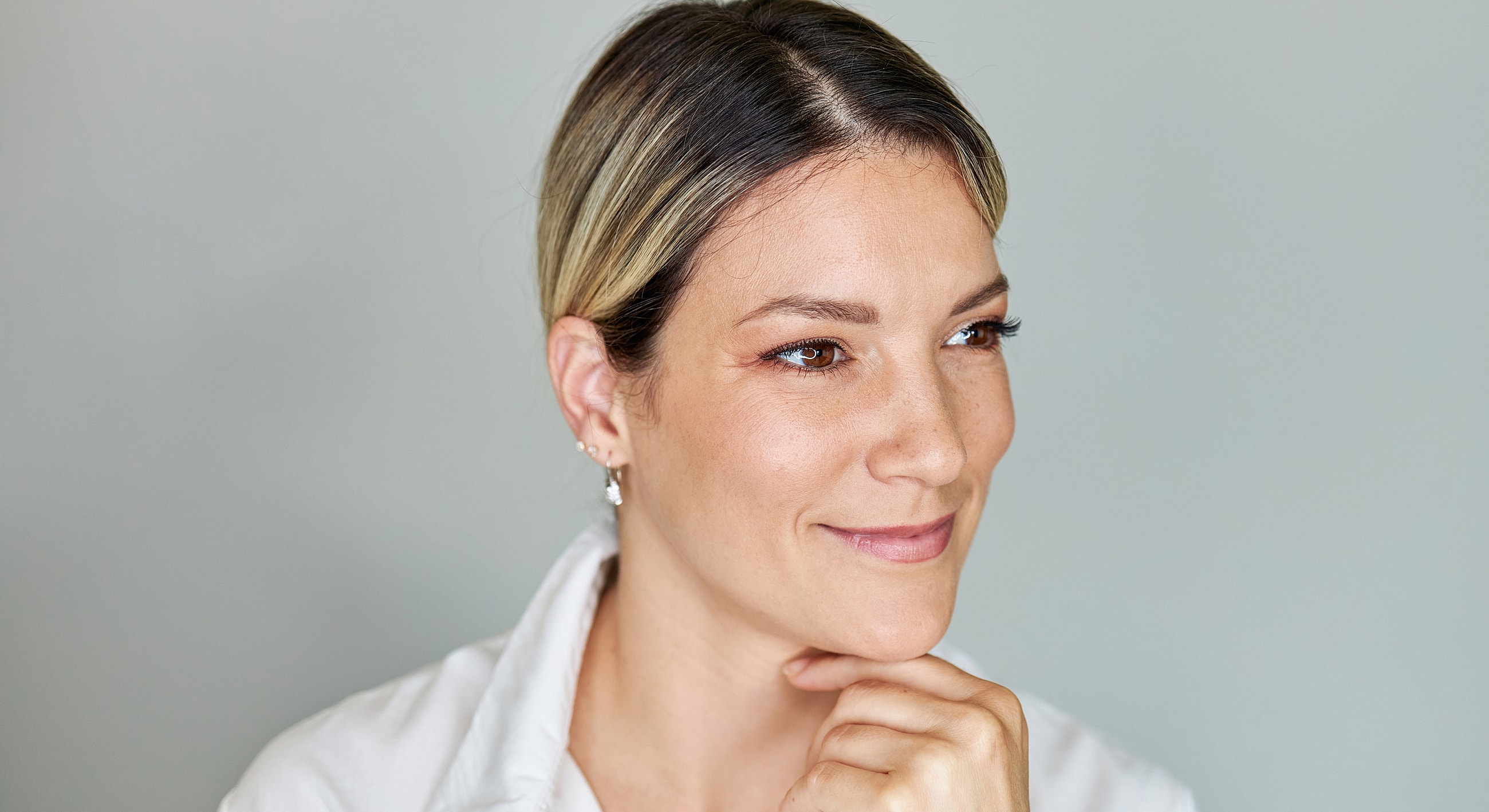 Smiling woman with chin on hand, thoughtful expression.