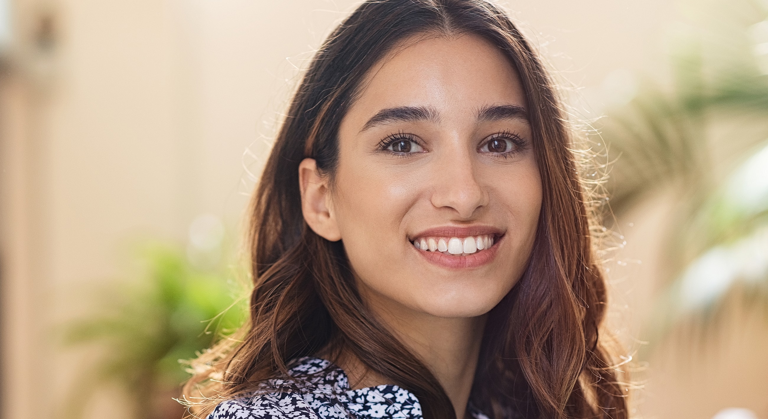 Smiling woman in a floral top, indoors.