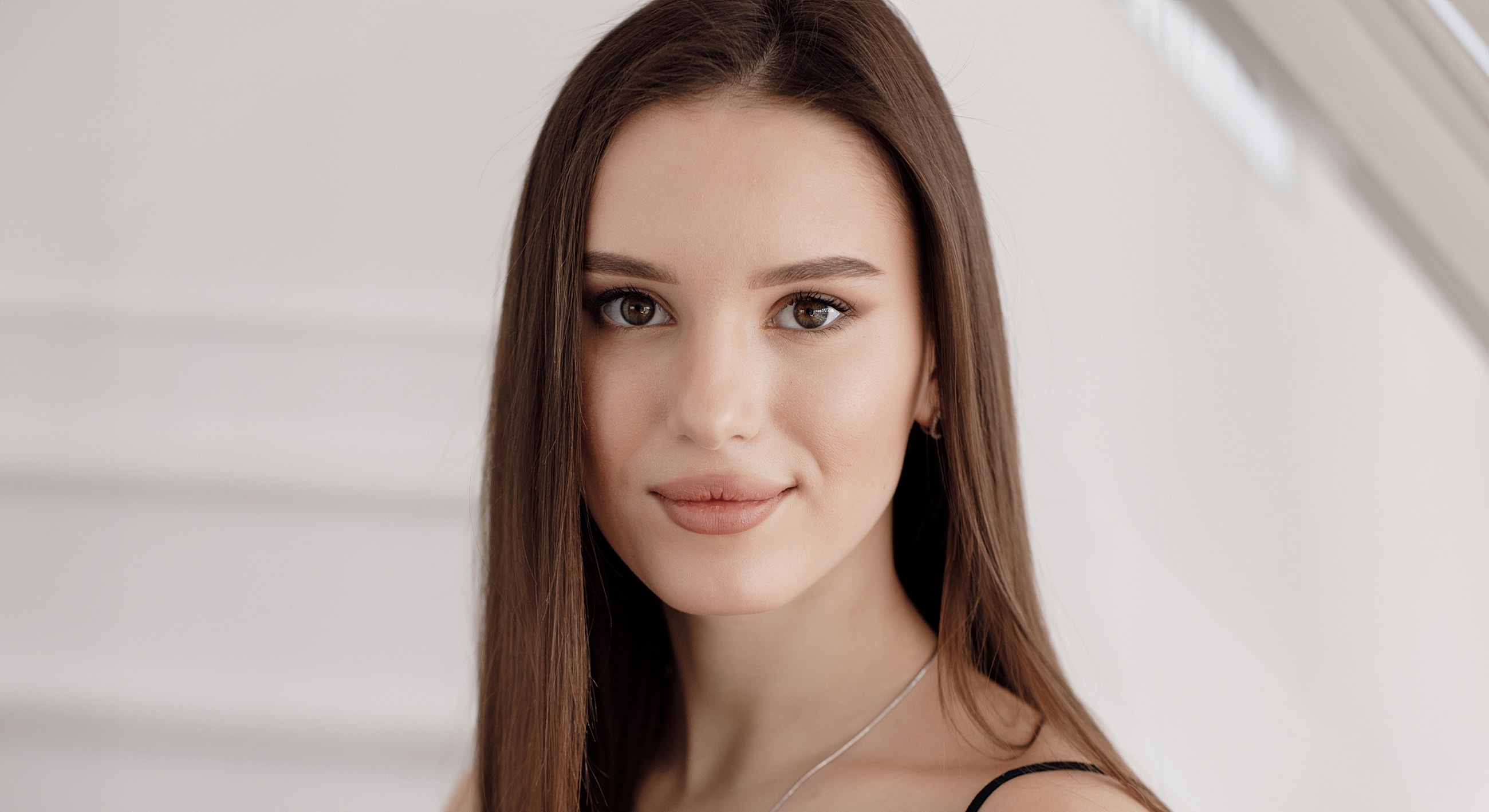 Young woman with long hair, neutral expression.