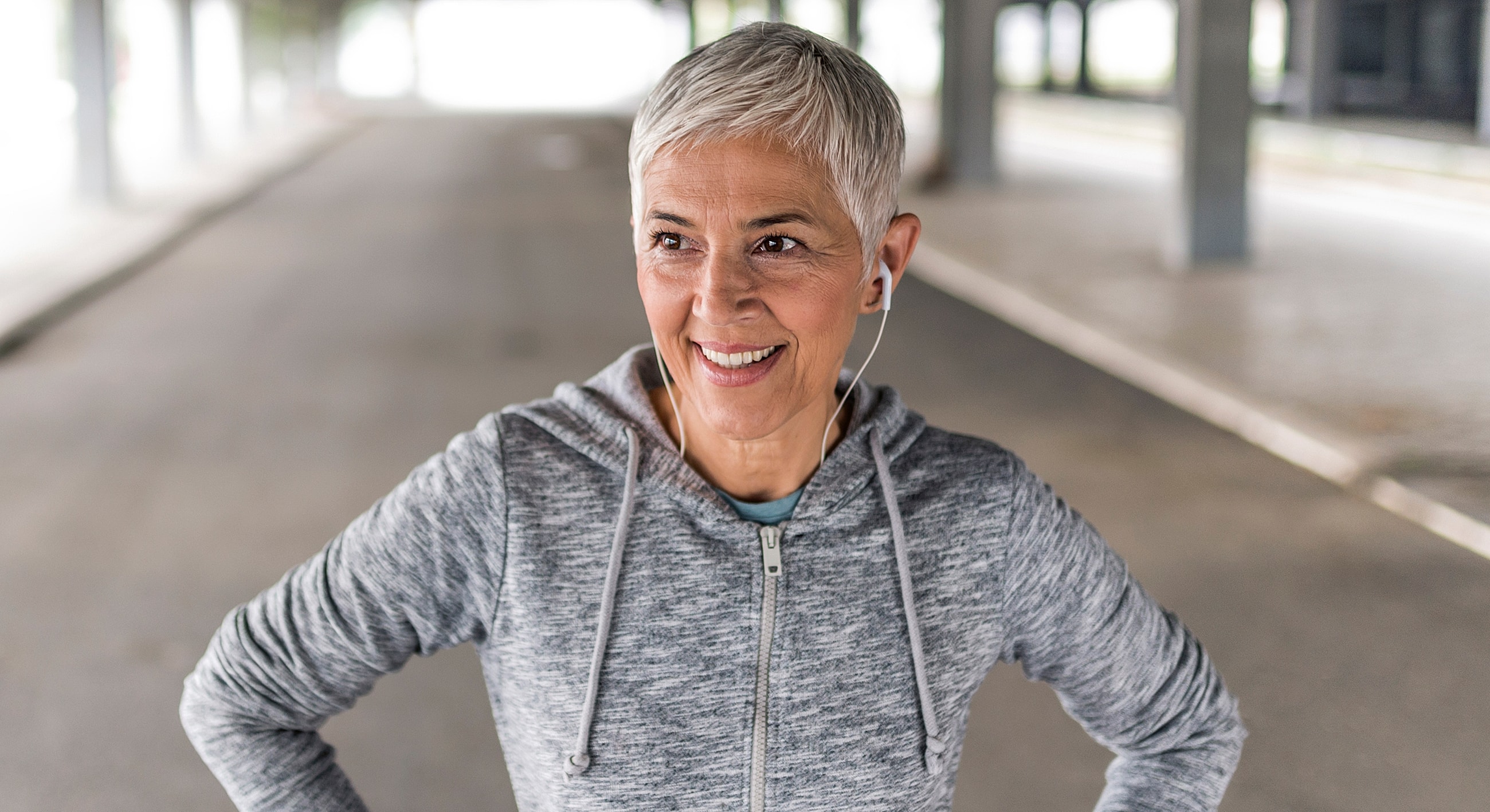 Smiling older woman in workout attire with headphones.
