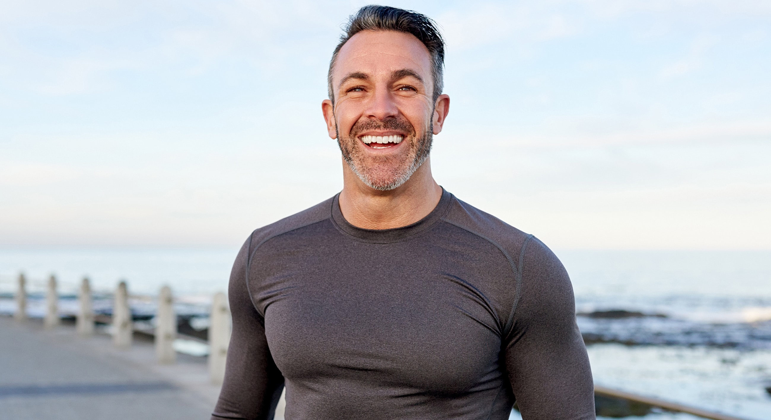 Smiling man standing by the ocean.