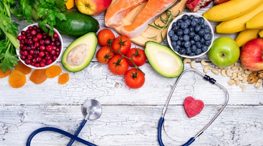 Healthy fruits and vegetables alongside a stethoscope and a small woodblock of a heart