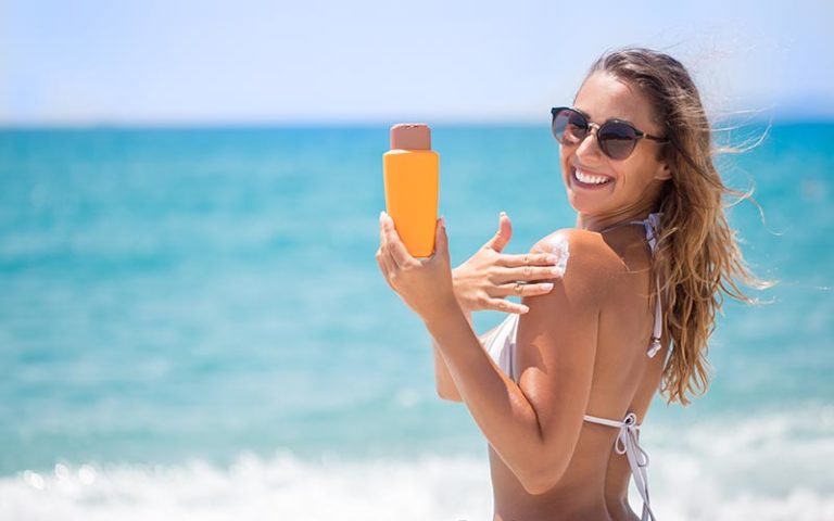 Beautiful girl in bikini applying sunscreen cream on the beach - Use Sunscreen Every Day